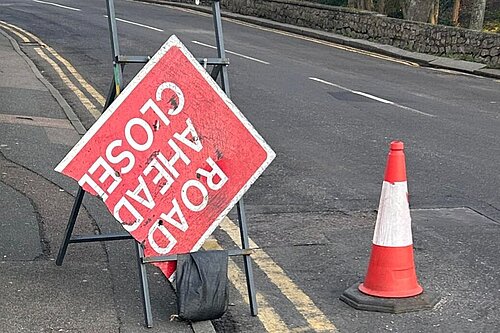 Broken Road Ahead Closed sign with traffic cone