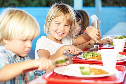 Four children eating food from a plate.